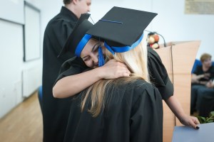 College graduates hug after ceremony.