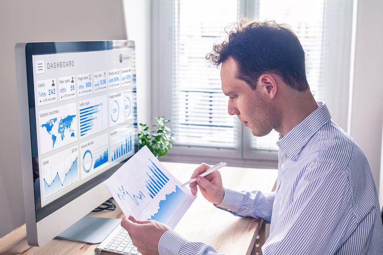 A communications professional studies an analytic dashboard that is displaying user demographics and data.