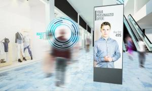 A shopper walks past a personalized digital display of a men’s shirt advertisement at a mall.