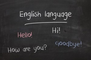 A photo of a blackboard, with the words “English Language; Hello! Hi! How are you? Goodbye!” written on it in different colored chalk.