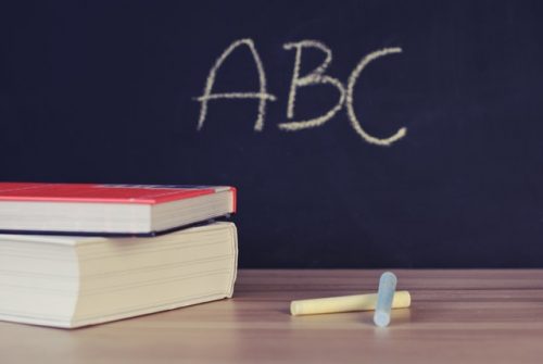 ABC written in chalk on blackboard with two books stacked in front