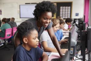 Teacher assists students individually in a computer lab