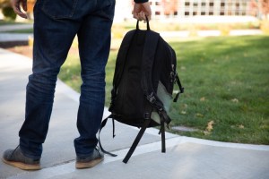 student holding backpack by legs