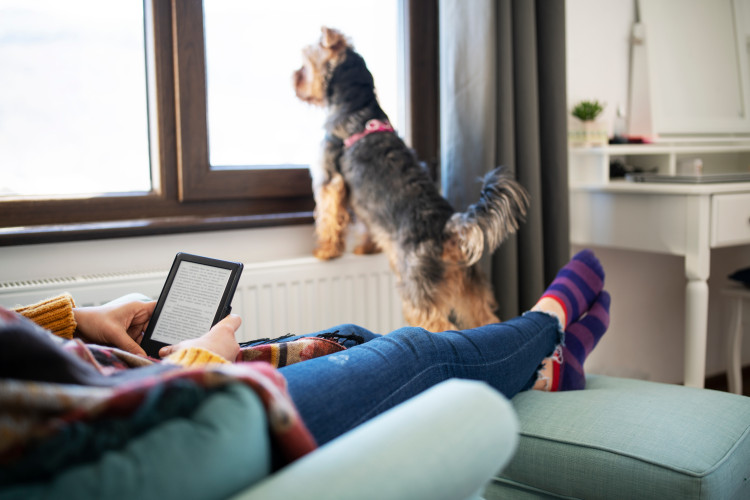 woman lounging with e-reader and dog nearby