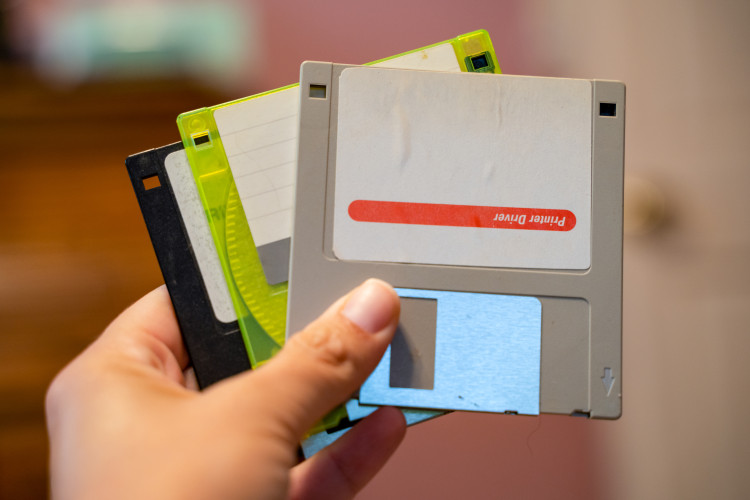 A hand holds three floppy disks