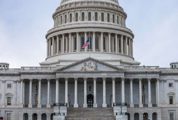 The U.S. Capitol building’s east facade is shown with the U.S. flag flying in front of it.