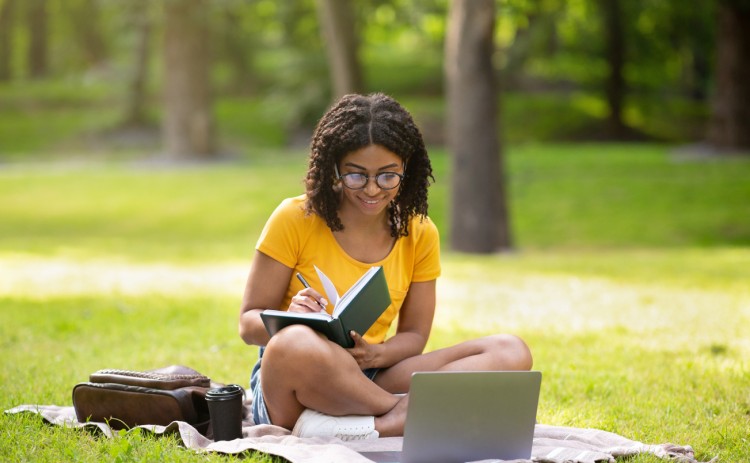 A college student doing homework in the park.