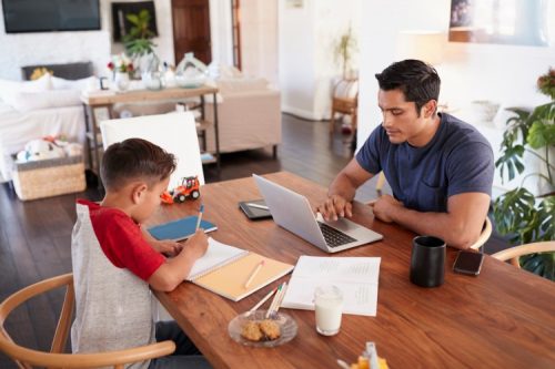 A parent and child study together at a table.