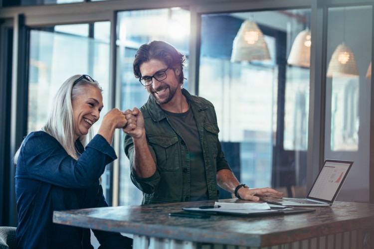 Smiling coworkers bump fists.