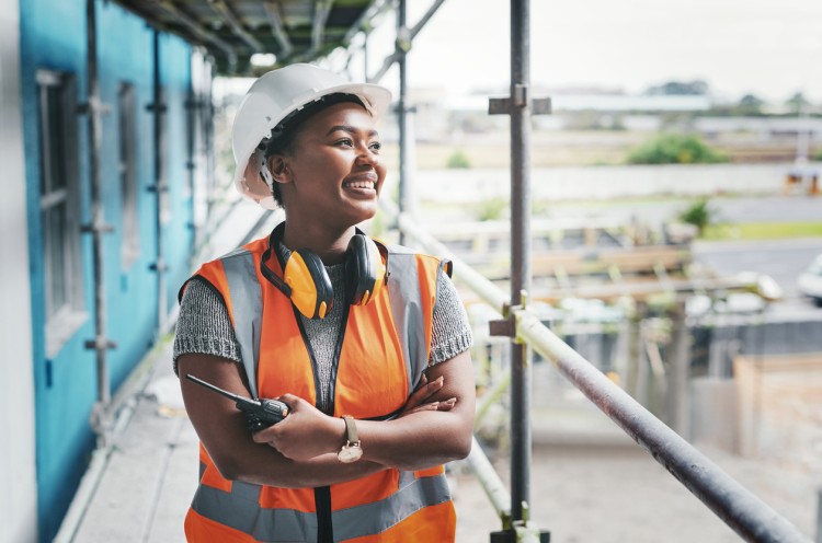 A smiling worker wearing a helmet and reflective vest.