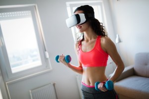 An athlete uses VR goggles and hand weights for a virtual exercise program.