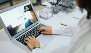 An individual conducts an online job search using a laptop.