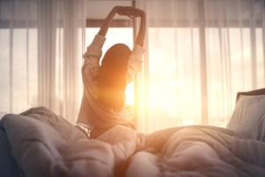 A person waking up and stretching in bed.