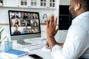 A remote worker waves to colleagues on a videoconference call.