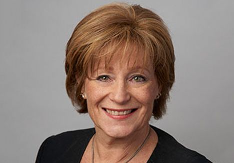 Karen Schechter, Director and Assistant Professor of Healthcare Administration Programs smiling with short, light-brown hair and poses against a neutral grey background.