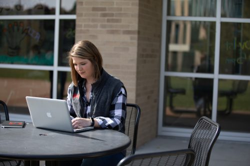 student sitting outdoors on her computer