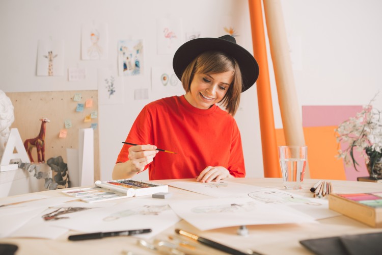 An illustrator is working on a watercolor image in a studio. 