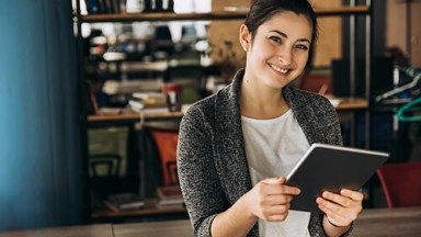 Smiling woman holding tablet in open office