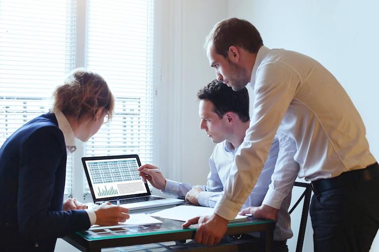 Group of Actuaries gathered by computer analyzing data.