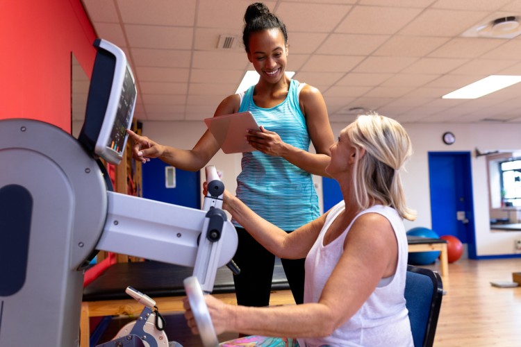 An athletic trainer works with a client on an exercise machine