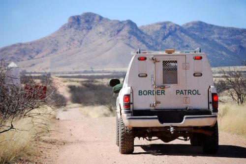 A CBP officer patrols a road near the border in a CBP vehicle.