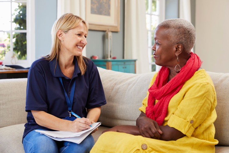 A case management assistant meets with a senior woman in their home.