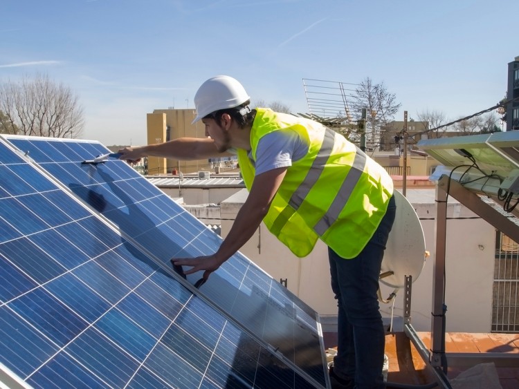A technician cleans solar panels.