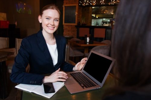 Female profesional sitting down with laptop and phone on desk