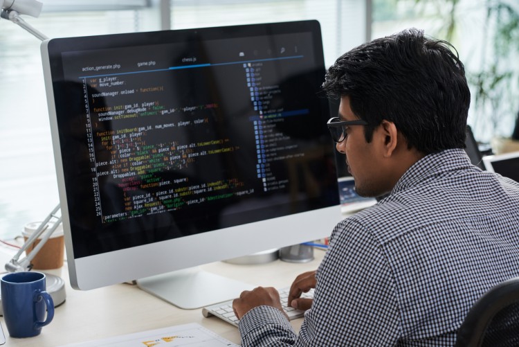 A cybersecurity professional reviews code on a desktop monitor.