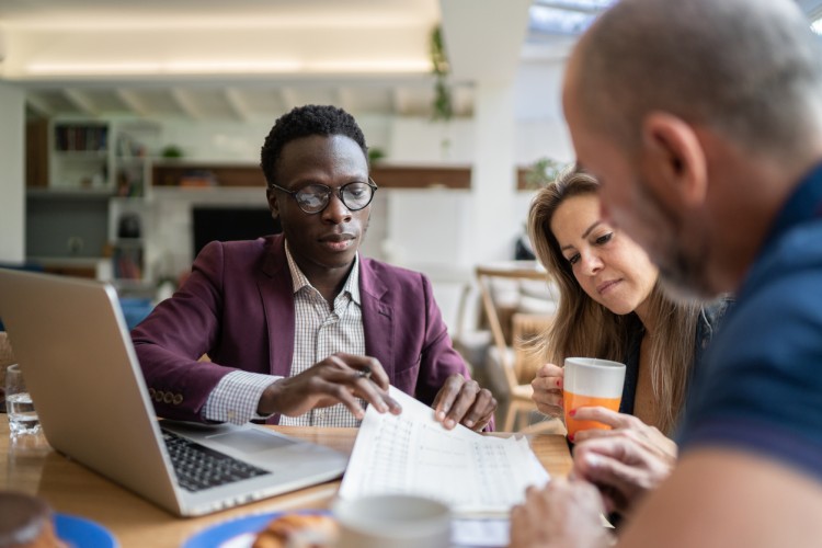 A financial advisor shows two clients a document.