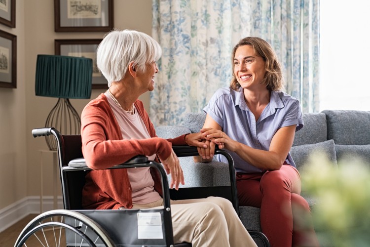 A geriatric social worker meets with a client who is in a wheelchair.