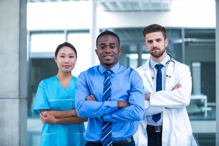 A health manager stands with a doctor and a nurse in a hospital