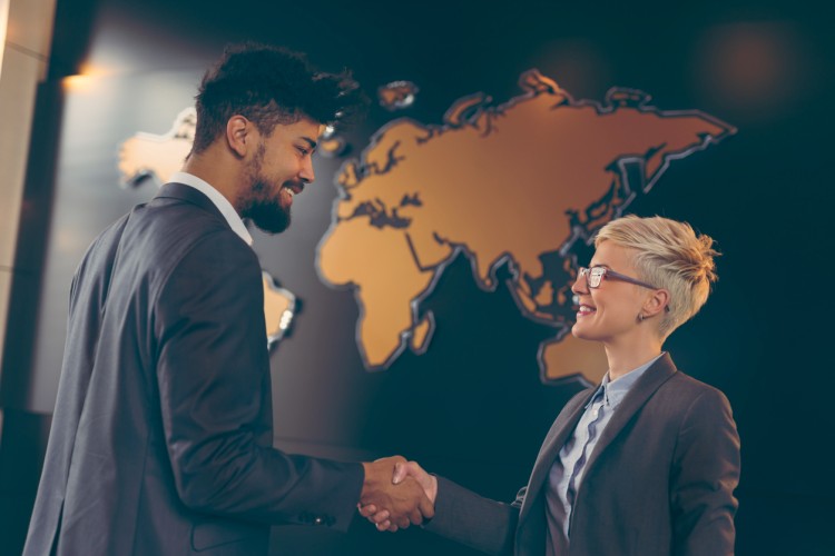 An international trade specialist shakes hands with a company CEO.