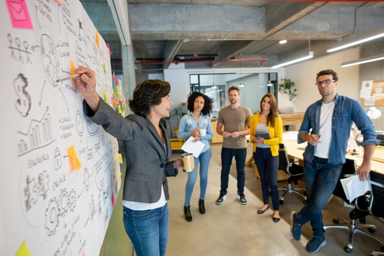 A marketing specialist briefs their team using a whiteboard.