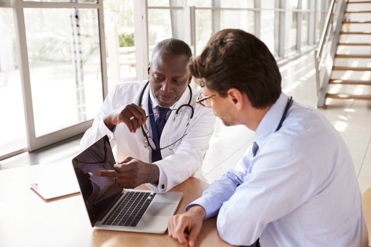 A medical sales rep shares a presentation with a doctor on a laptop
