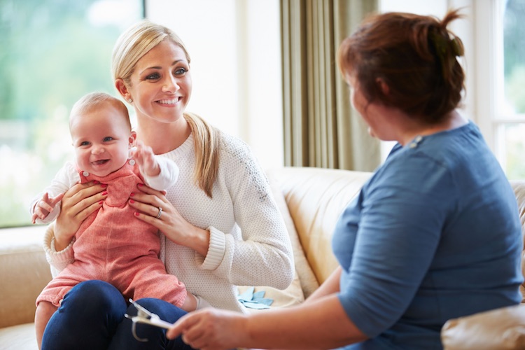 Mother holding her toddler while speaking to a home health manager