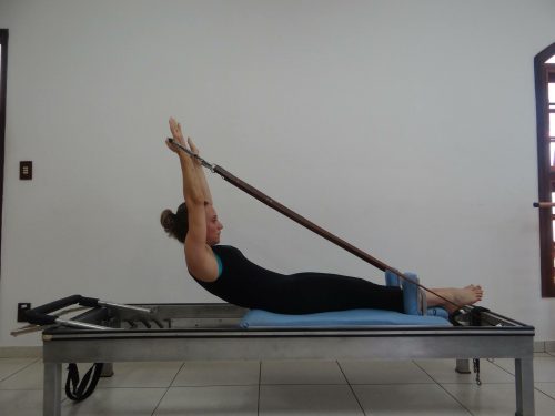 A woman uses physical therapy equipment to do a Pilates exercise.