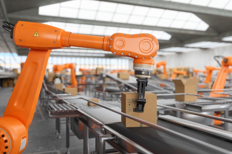 A robotic arm places a package on an assembly line.
