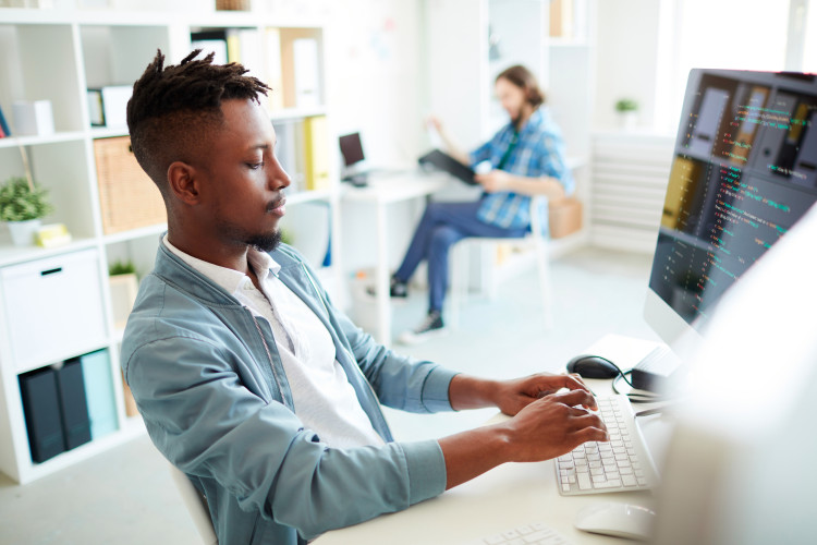 a man sitting at a desk in front of a computer typing on a keyboard