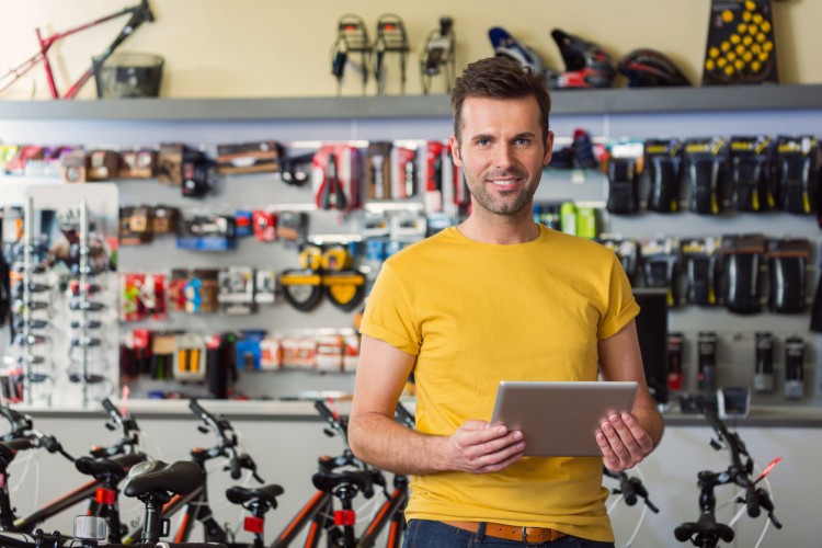 Salesman standing near showcase with fishing equipment in sports