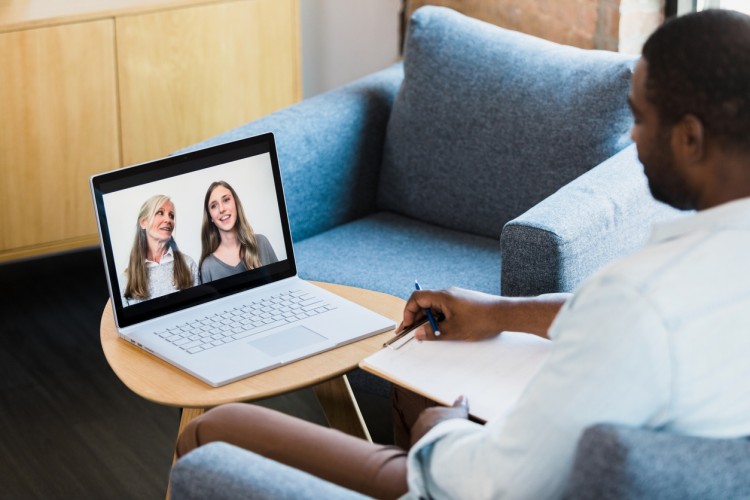 A therapist meets with clients using a laptop to videoconference.