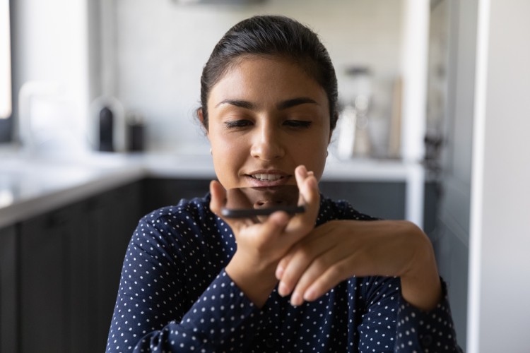 A person holding a cellphone speaks to a digital assistant.