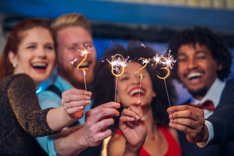 A group of people holding up sparklers that number “2023.”