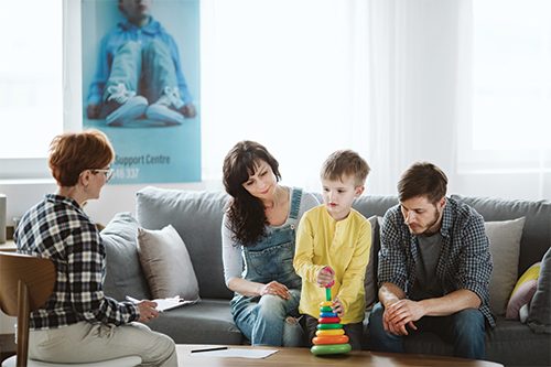 mother son and father talking to a woman in living room