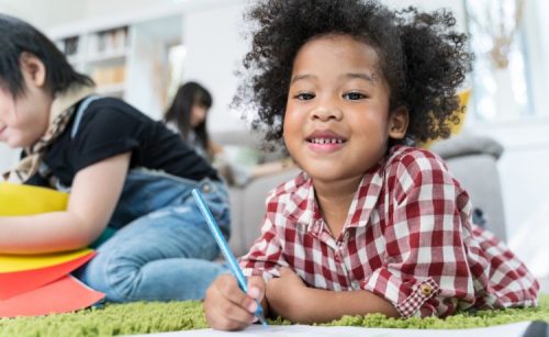 A preschool child draws with a colored pencil in a classroom