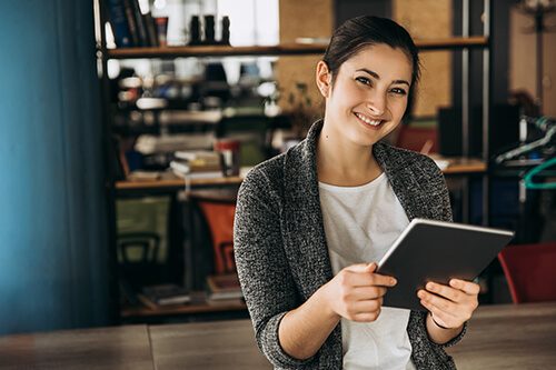 Smiling woman holding tablet in open office