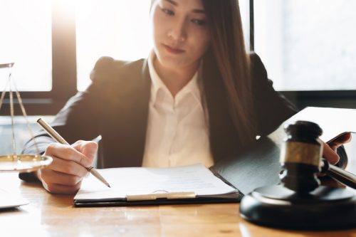 A criminal psychologist with a thoughtful expression goes over her notes with a gavel and scale nearby to symbolize the criminal justice system.