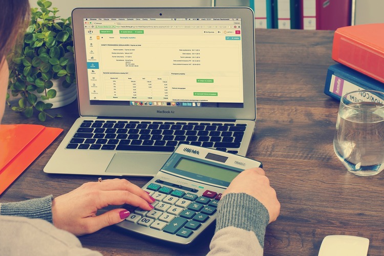 female using a calculator at a computer