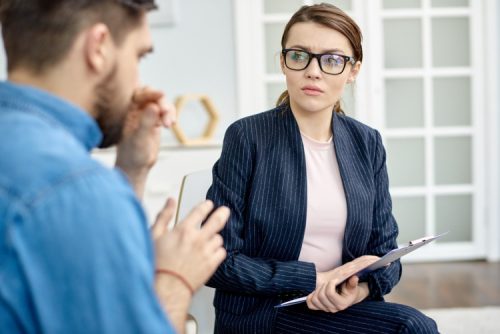 Woman holding clipboard listening to man