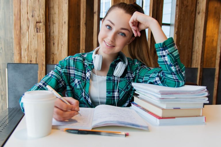 Young female student smiling and writing notes. 